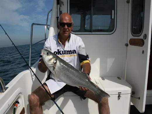 Visser met een zeebaars op de boot