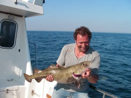 Visser met een kabeljauw op de boot